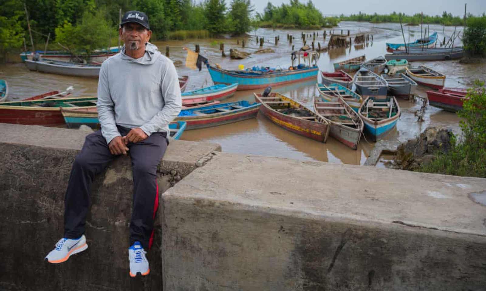 George Jagmohan sitting in front of a few boats.