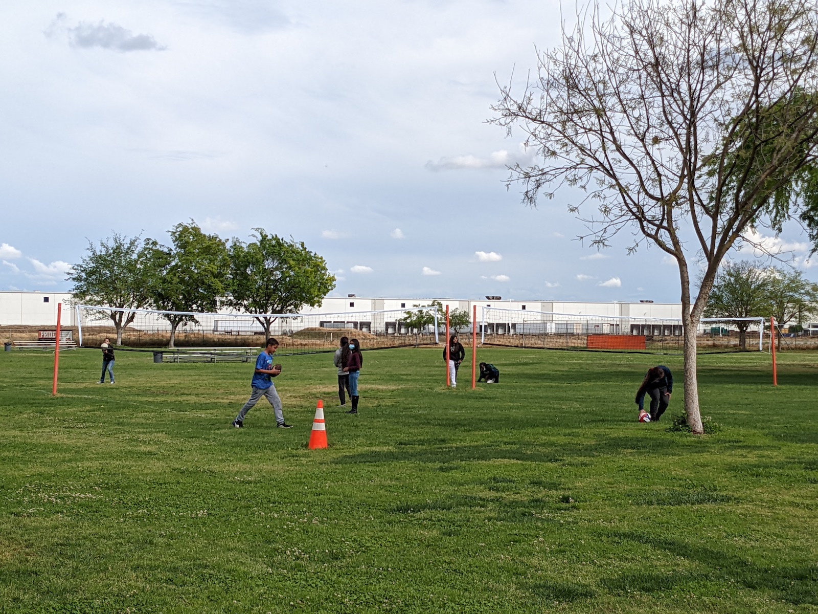 kids hold volley balls near nets with warehouse in background