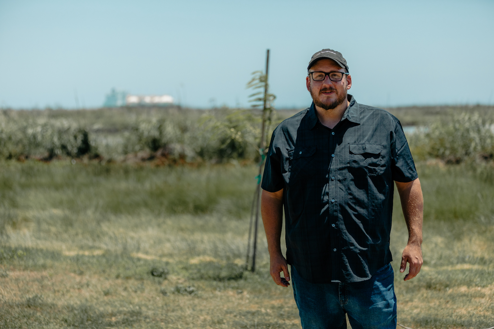 A man stands with a cargo ship in the background