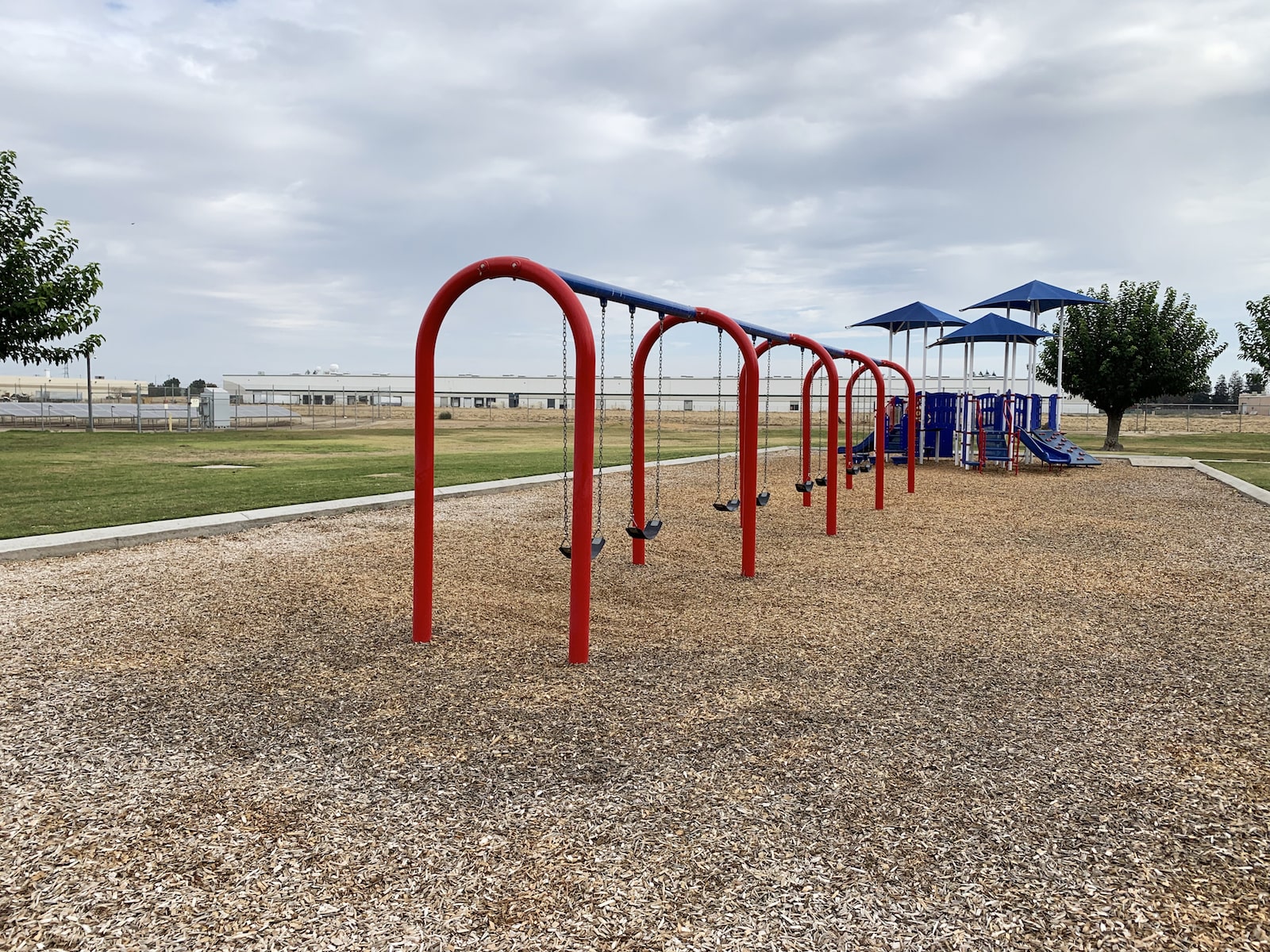 warehouses in the background of a red swing set and play structure