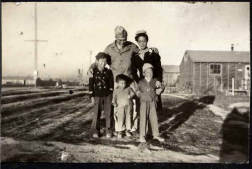 A black-and-white photo of a family of 5. The father is in army uniform; there are three young sons from a toddler to around age 7.