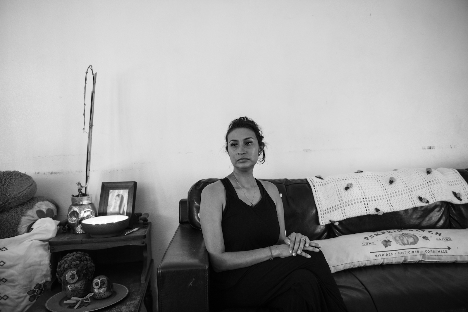 a woman sits on a couch in black tank top