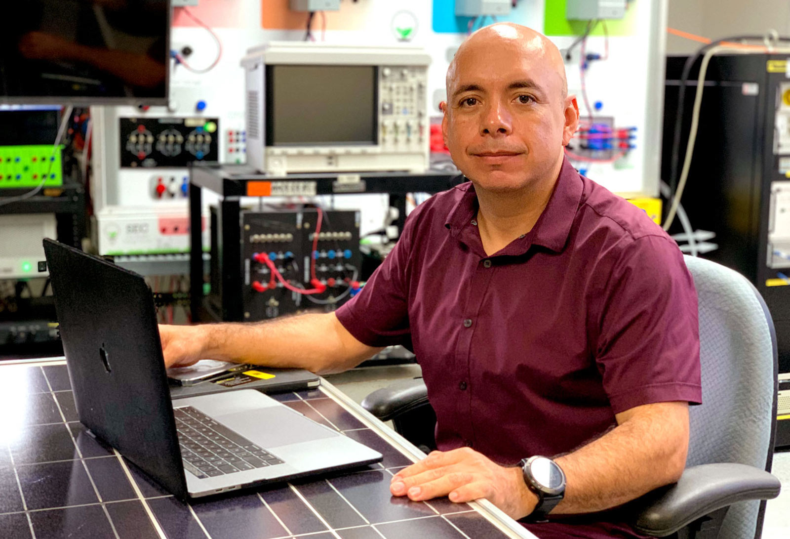 Fabio Andrade, seated at a table made from a solar panel, studies microgrids in Mayagüez, Puerto, Rico.