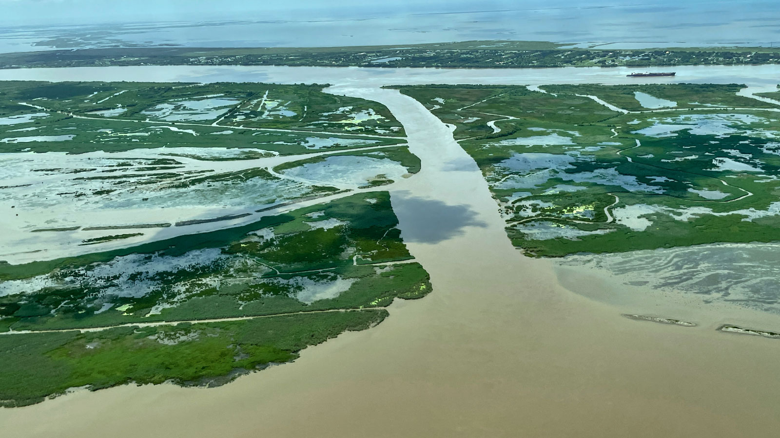 Aerial view of a channel of water attached to the Mississippi River with smaller areas of water scattered over the land