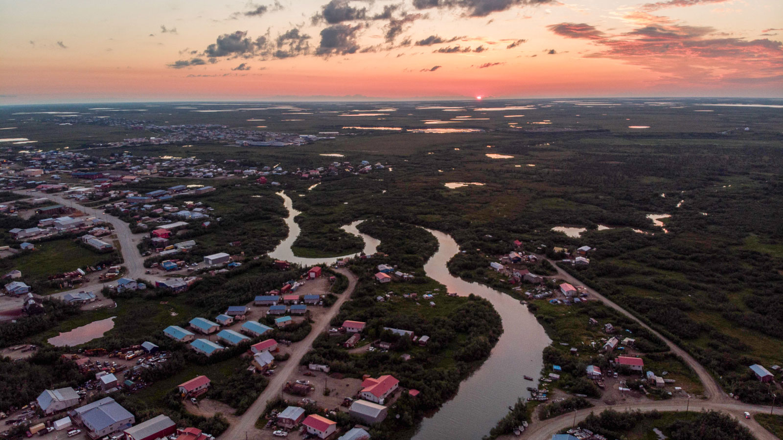 Aerial view of a village, with multiple houses and a river winding its way through the center