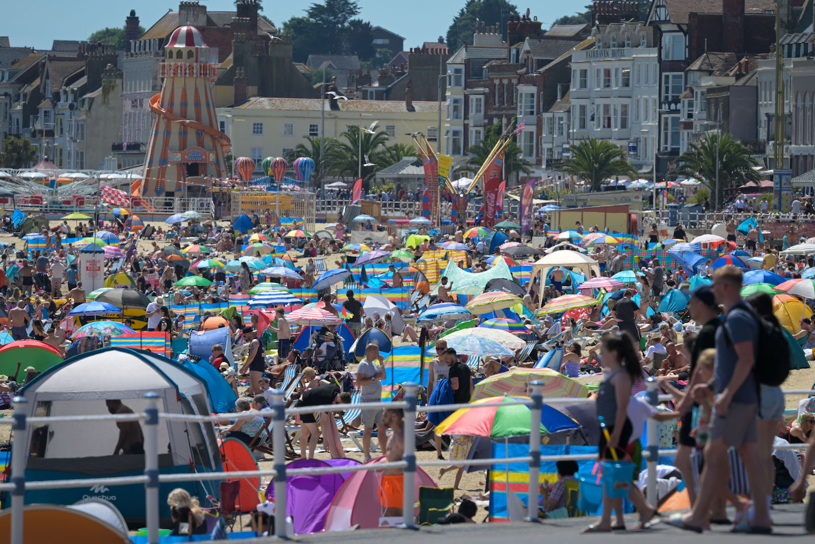 lots of people crowd at the beach with colorful umbrells