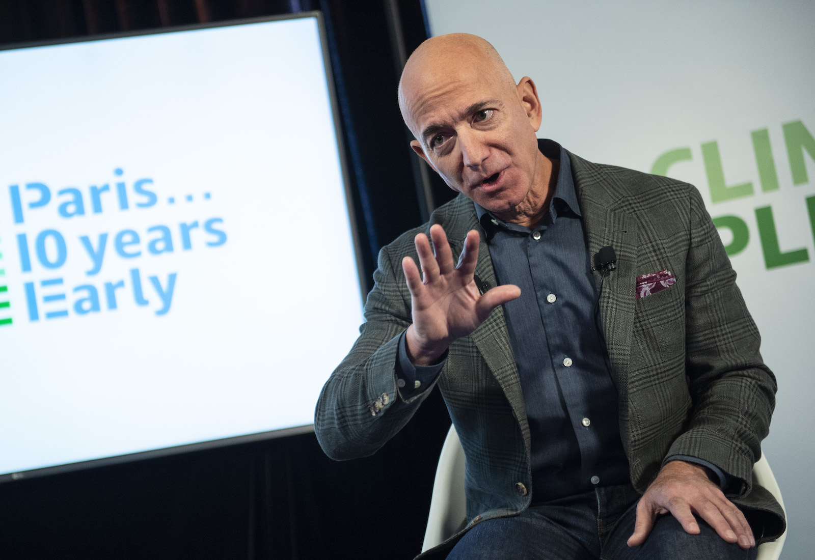 Former Amazon CEO Jeff Bezos speaks, while a poster behind him says "Paris 10 years early"