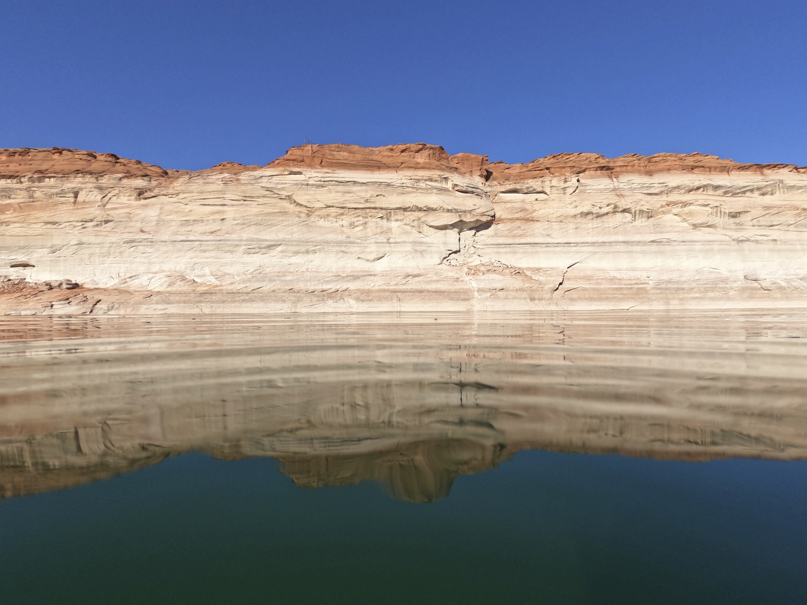 a dry white and yellow layer of rock relfects back down into a pool of water