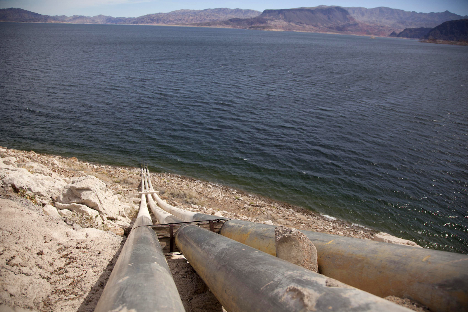 old-looking pipes stick out above a blue body of water