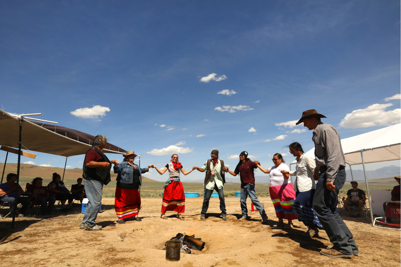 people hold hands in a half circle in the desert