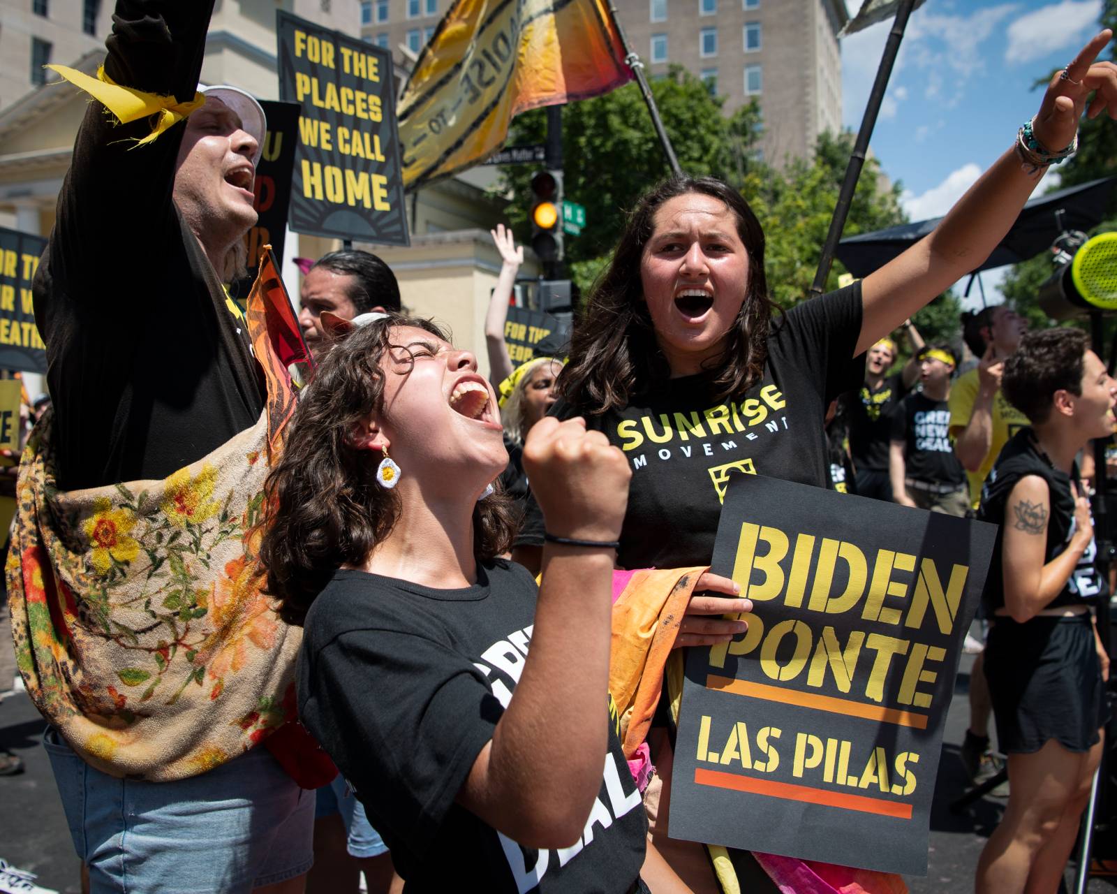 a group of people yell and wave signs