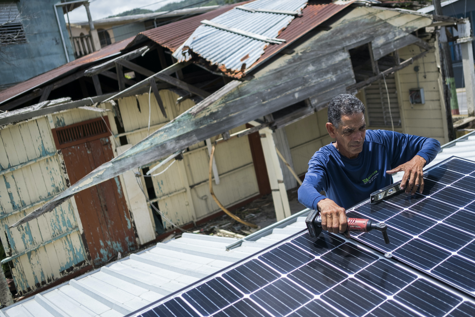 a man in a long-sleeve shirt holds a tool hovering over a rooftop solar panel