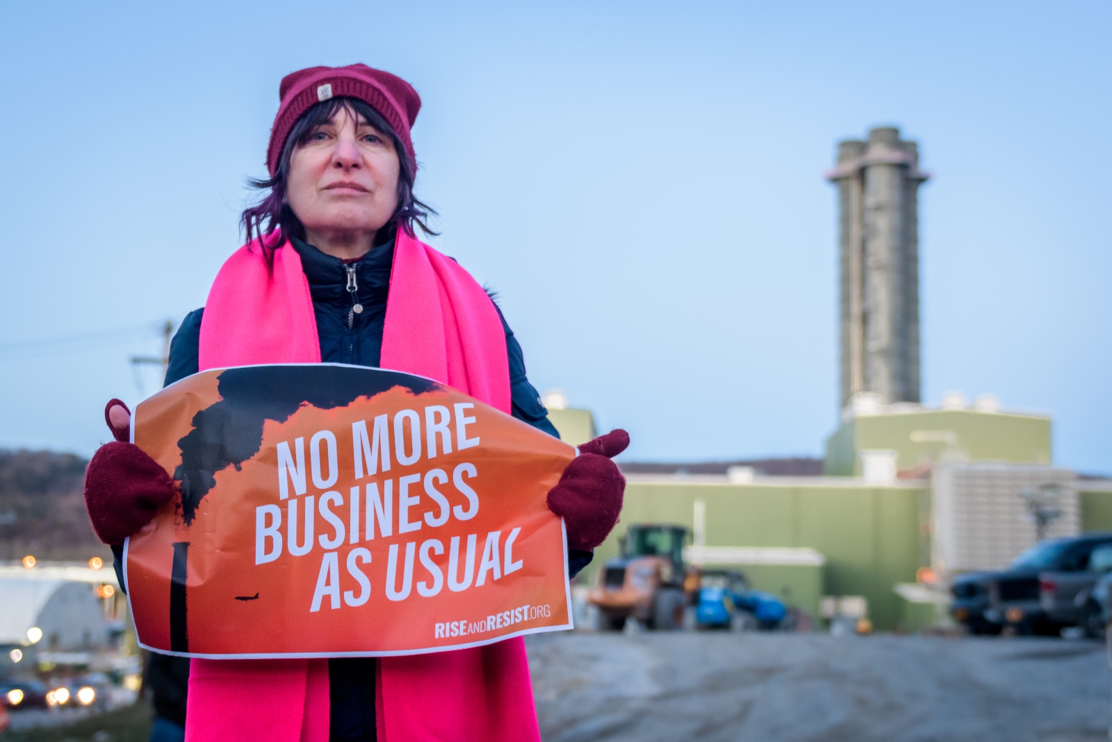 A person holds a sign saying "No more business as usual."