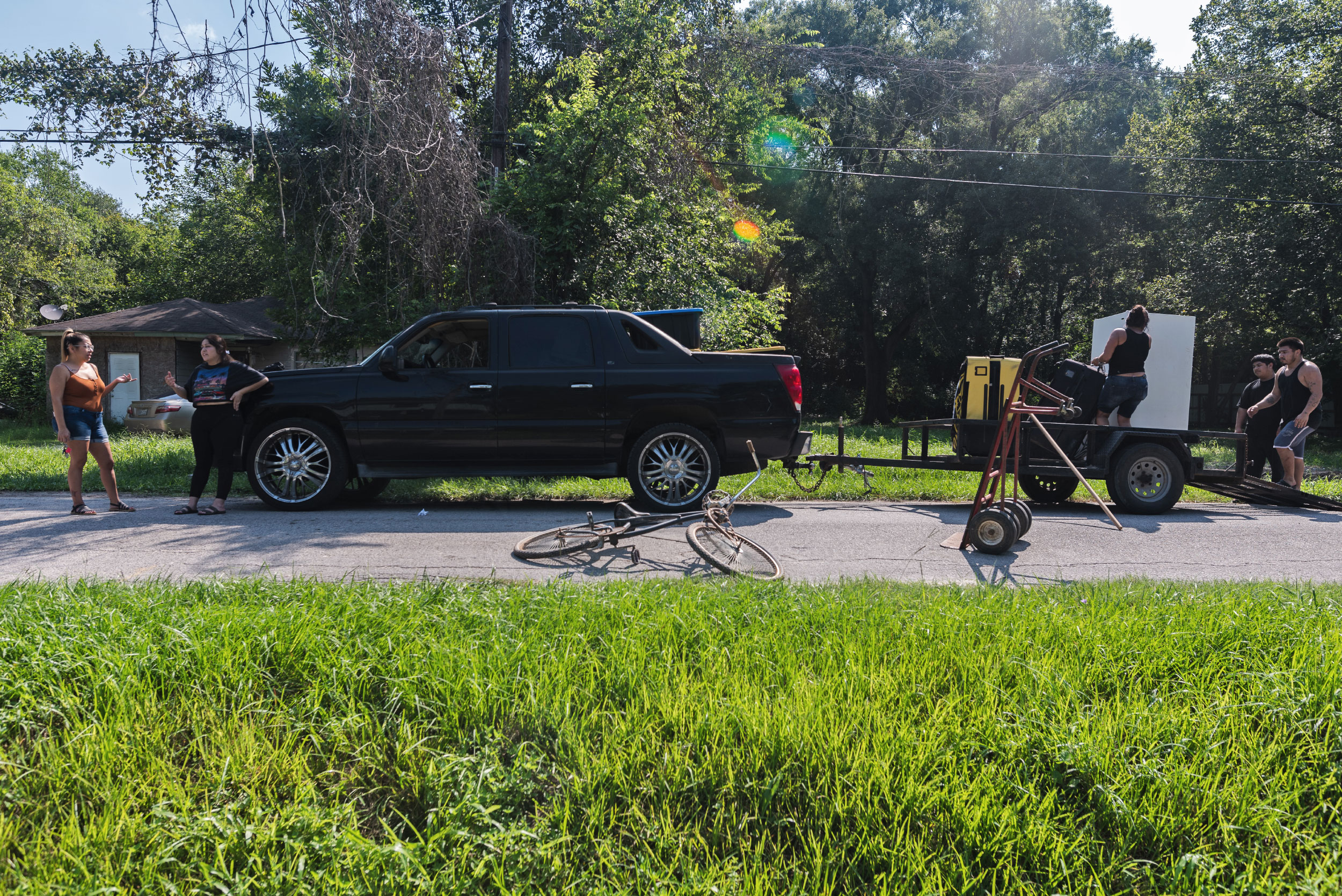 A woman talks with another woman while people load pieces of furniture into a truck