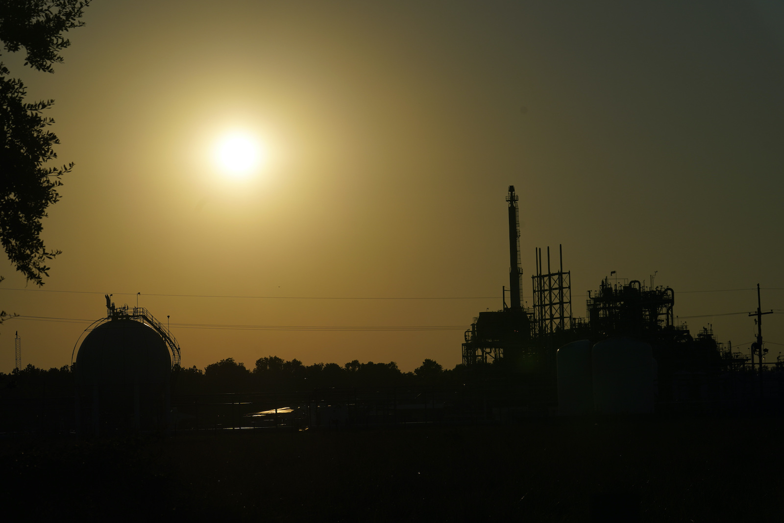 a sun and orange sky silhouetting a power plant