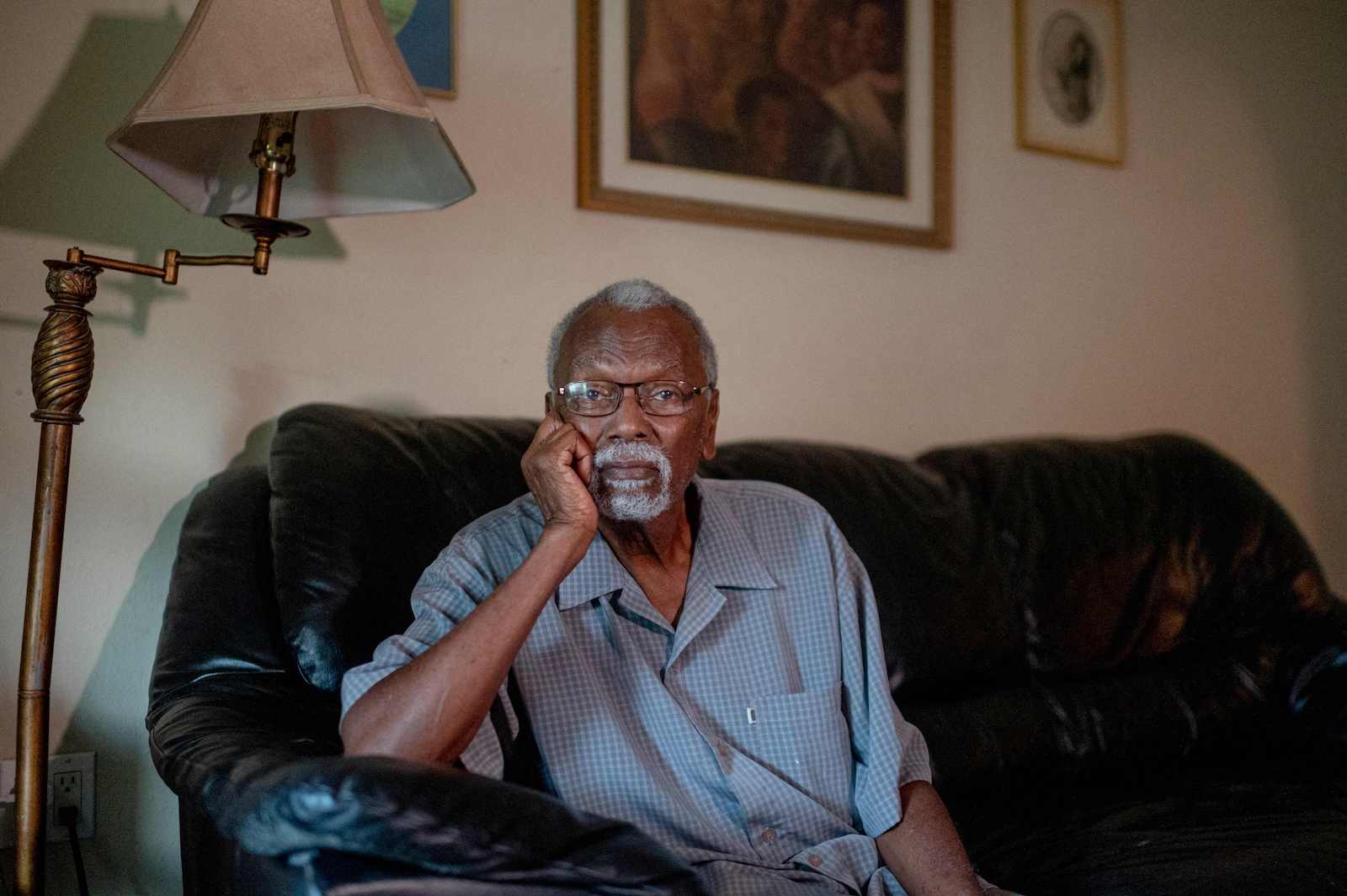 a man sits on a black couch inside of his house