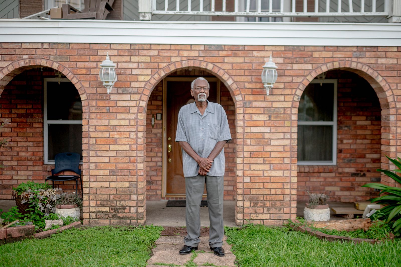 a man stands in front of brick house