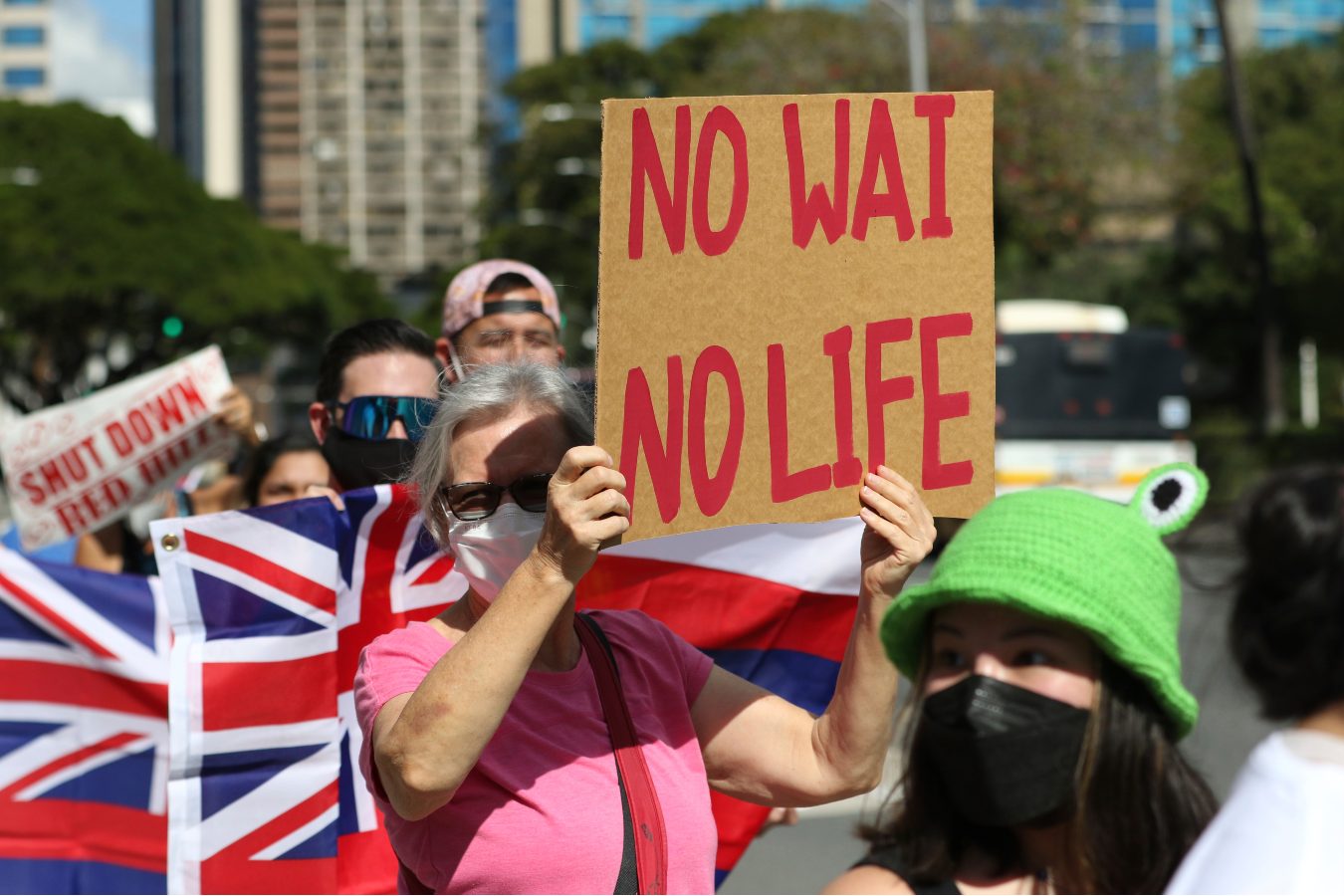 A woman wearing a face mask holds up a sign saying 