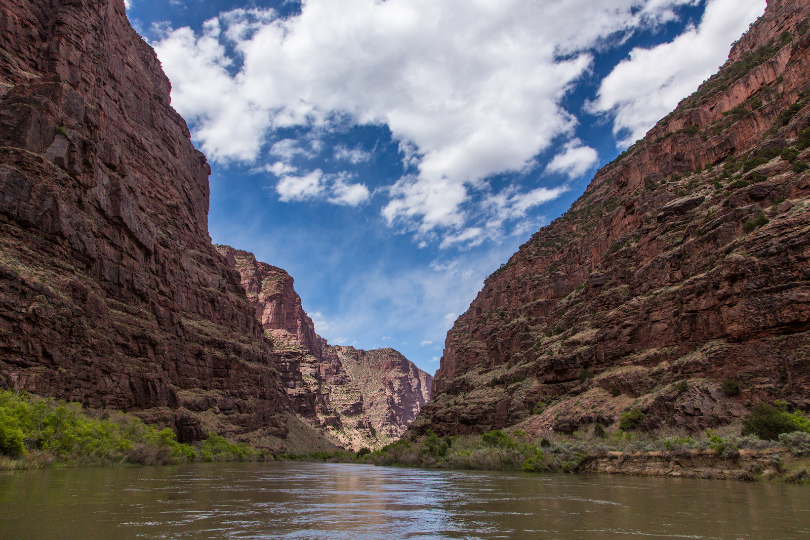 a river runs through a canyon under a cloudy sky