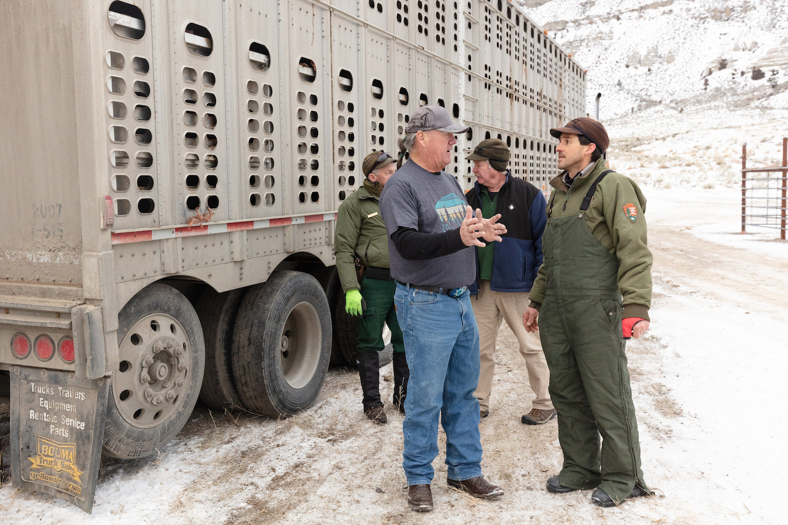 two men stand near a big truck with holes in it