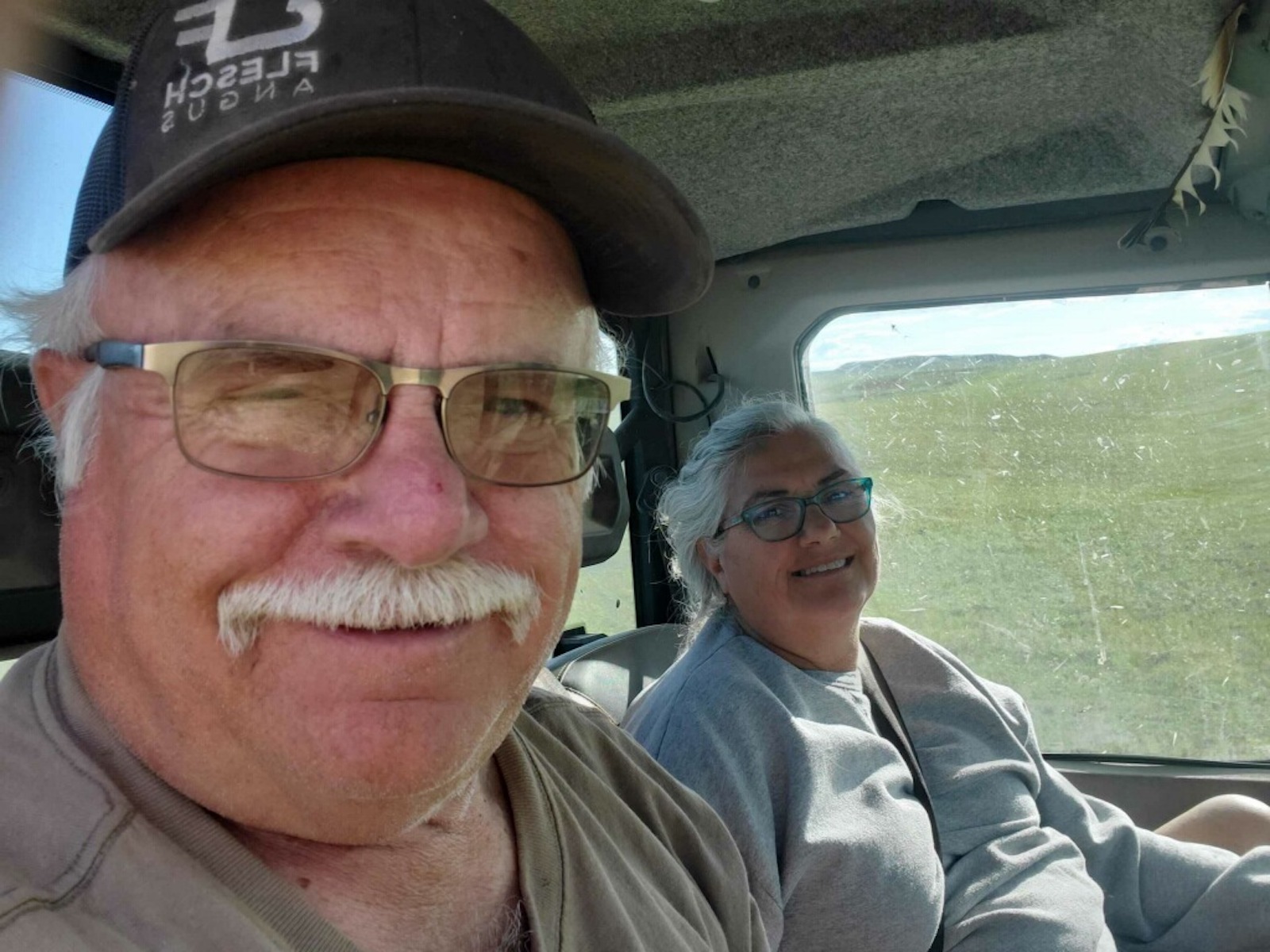 a man with a white moustache and a woman sit ina. car