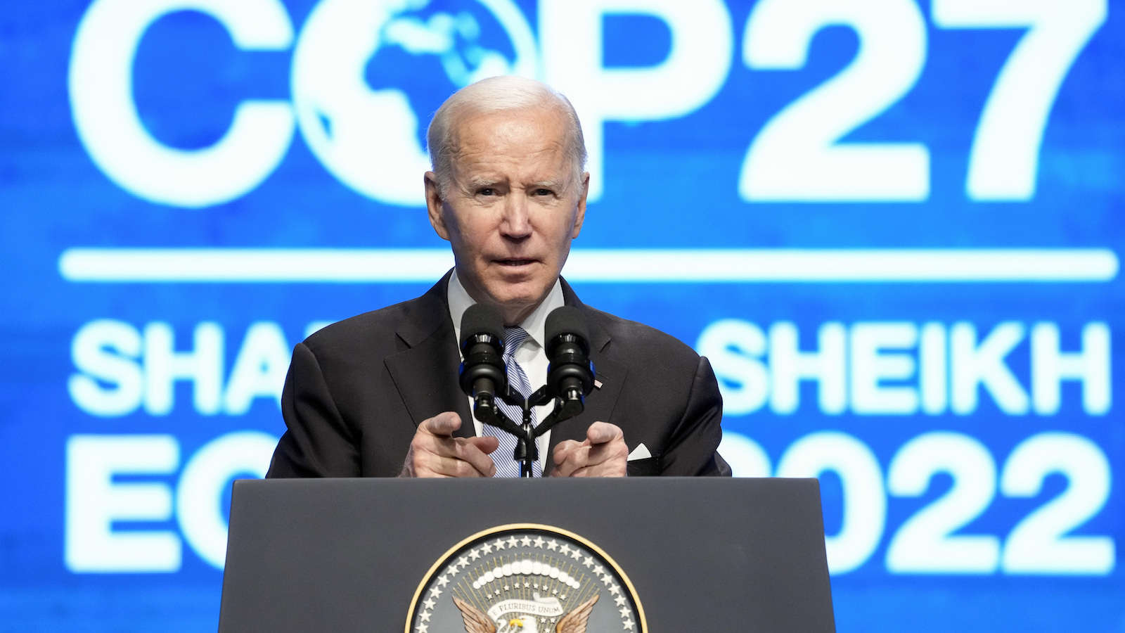 President Joe Biden stands in front of a blue background that says COP27