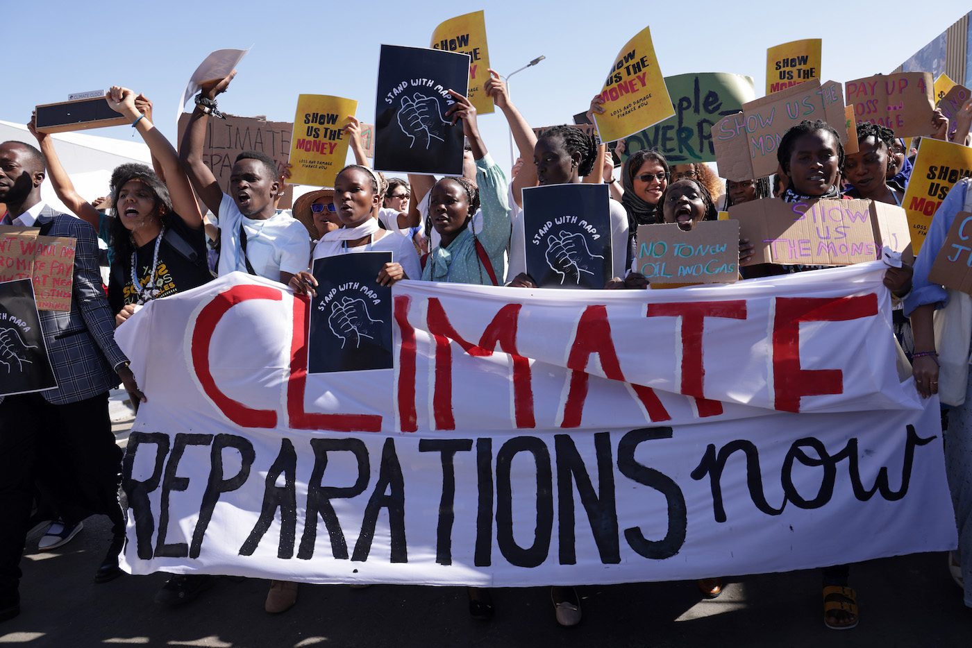 African protesters at COP27 with a banner that says climate reparations now