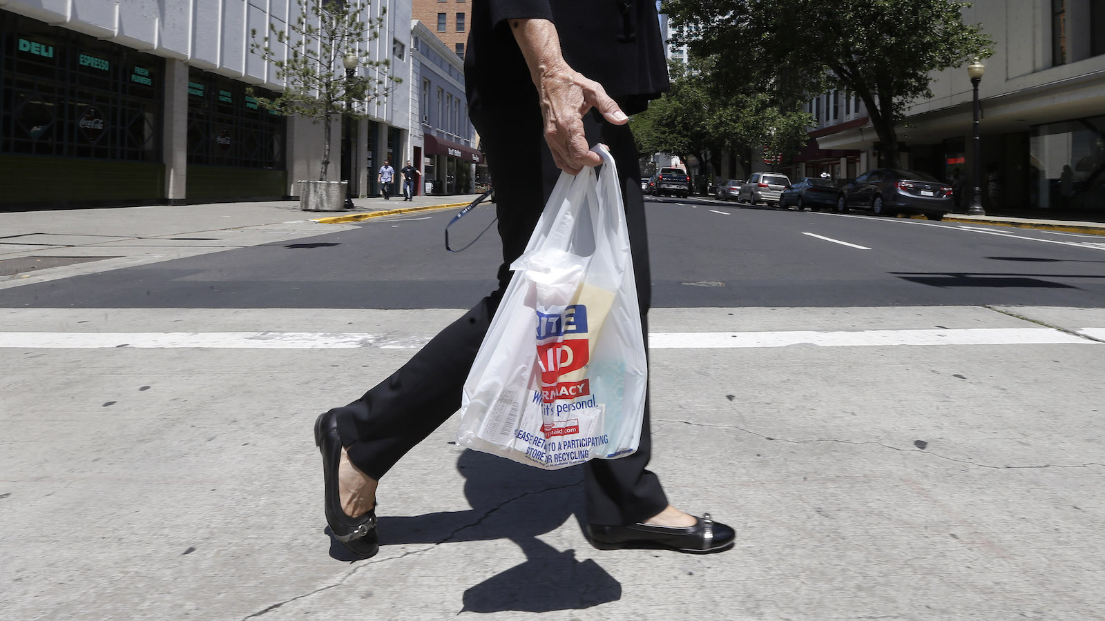 Someone wearing black carries a plastic bag.