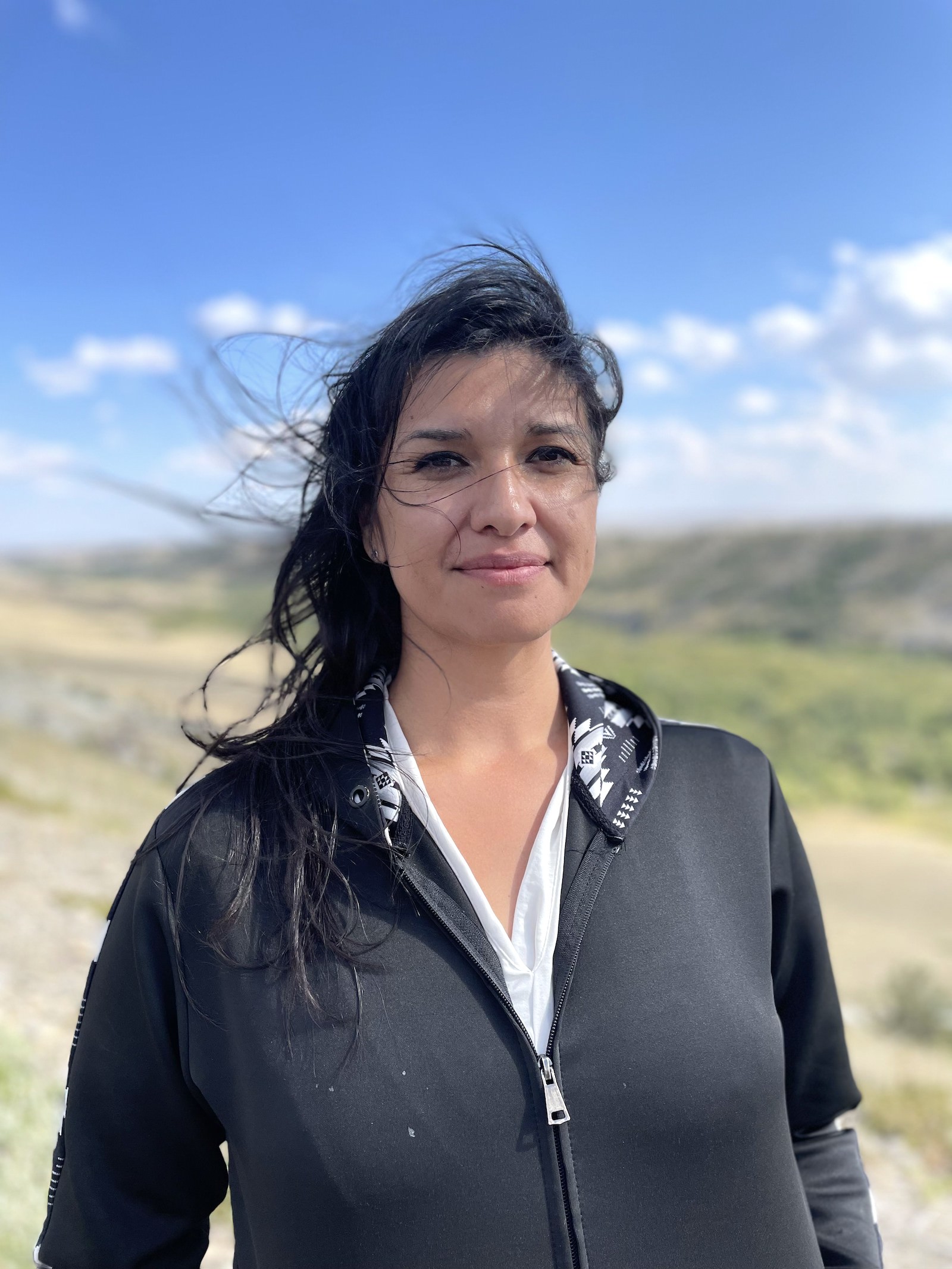 a woman with black hair stands in the wind