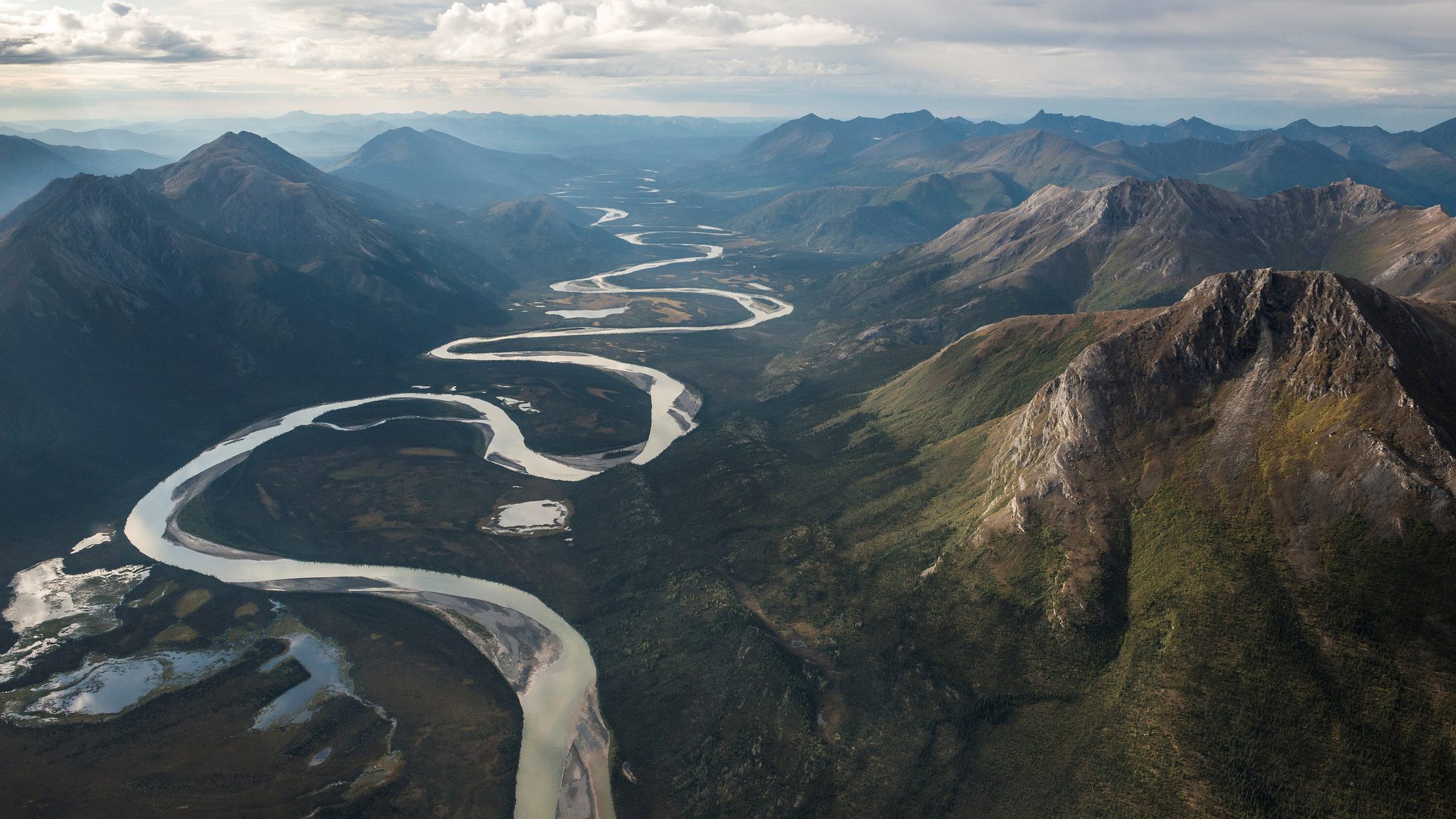 a vast mountainous landscape with a winding river running though the valley