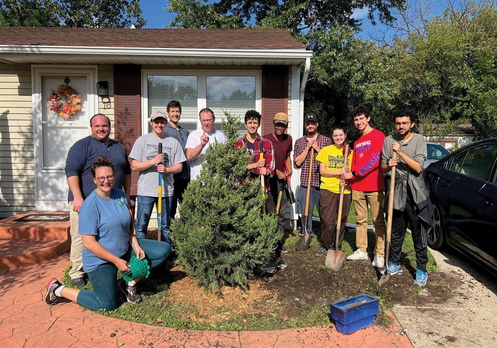 Group posing for a photo around a freshly planted tree