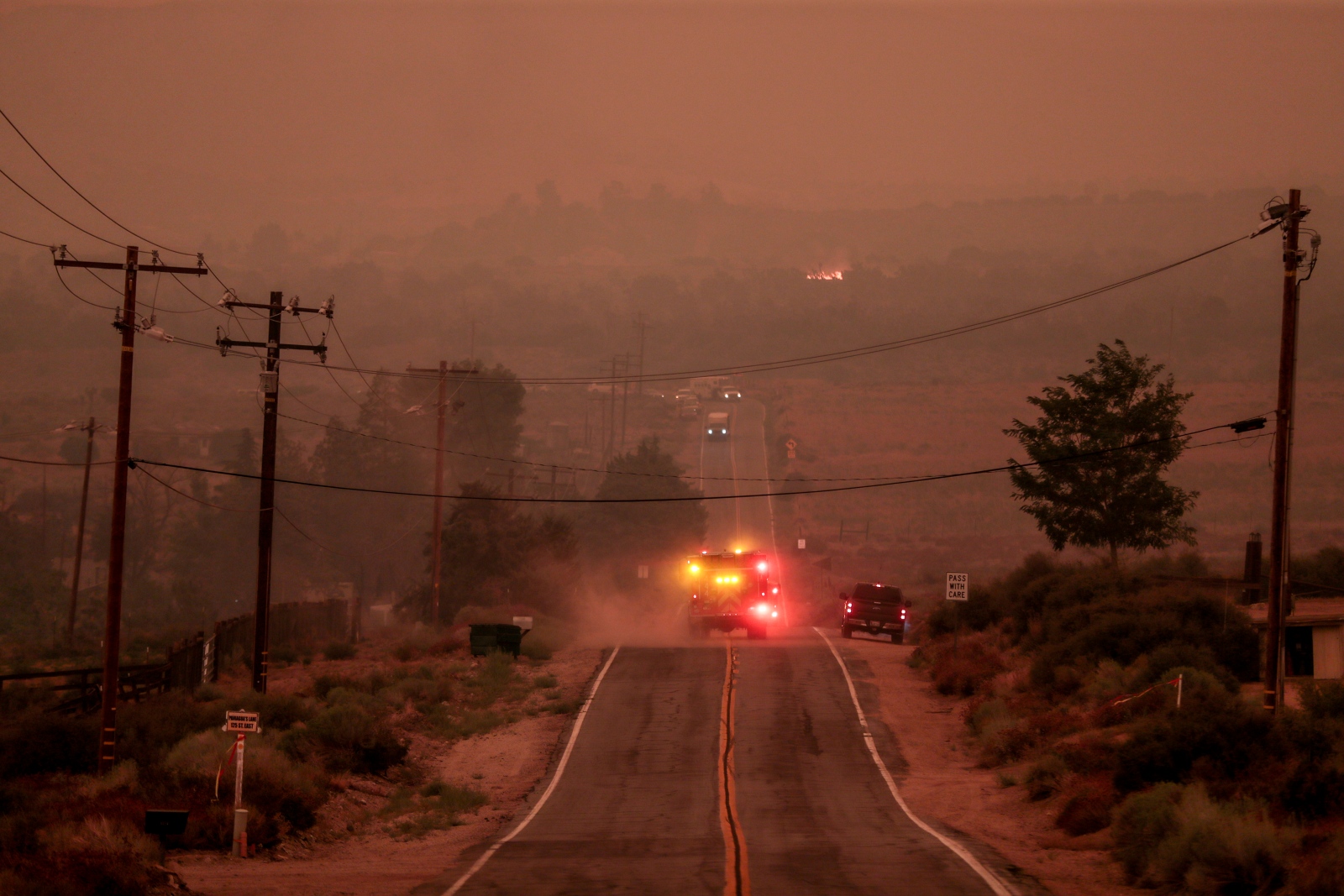 photo of a fire truck with its lights on surrounded by red smoke