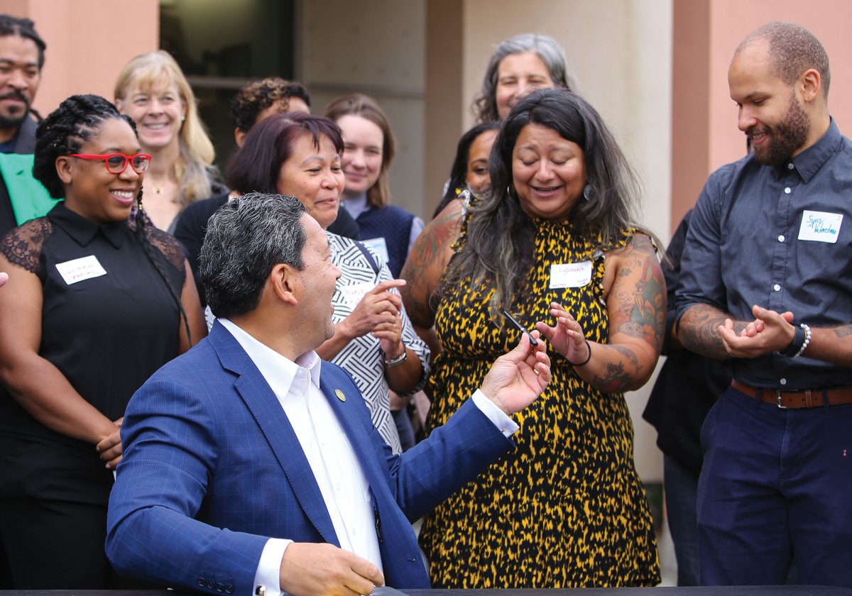 Seattle Mayor Harrell hands a pen to Lylianna Allala, Seattle Office of Sustainability & Environment Climate Justice Director, after signing Green New Deal budget investments