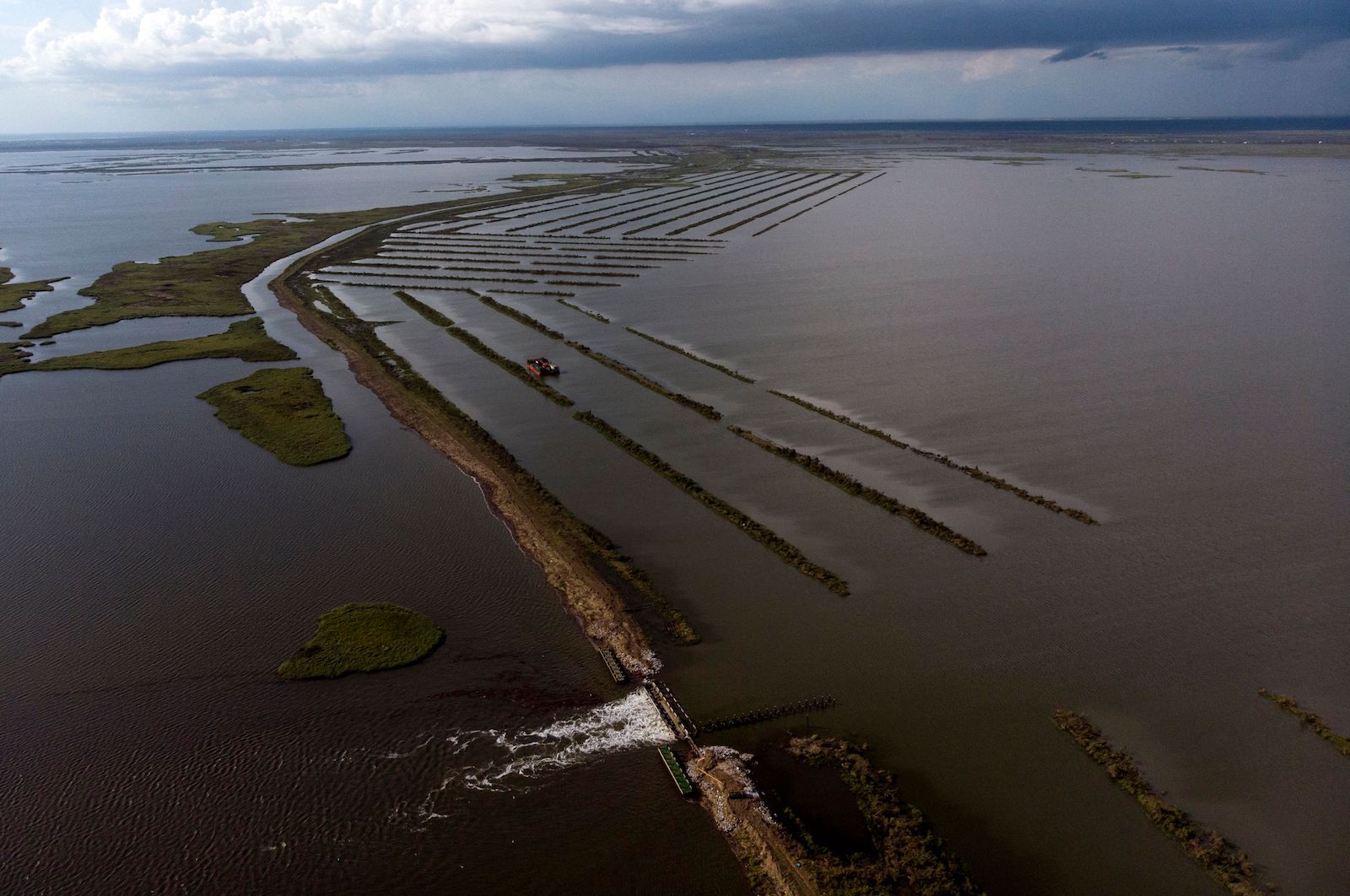 an aerial of a long thin wall structure curving near a coast line surrounded by water