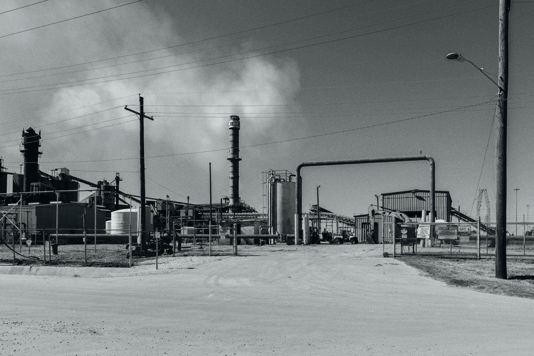 an indistrial facility with pipes and smokestacks under a cloudy sky