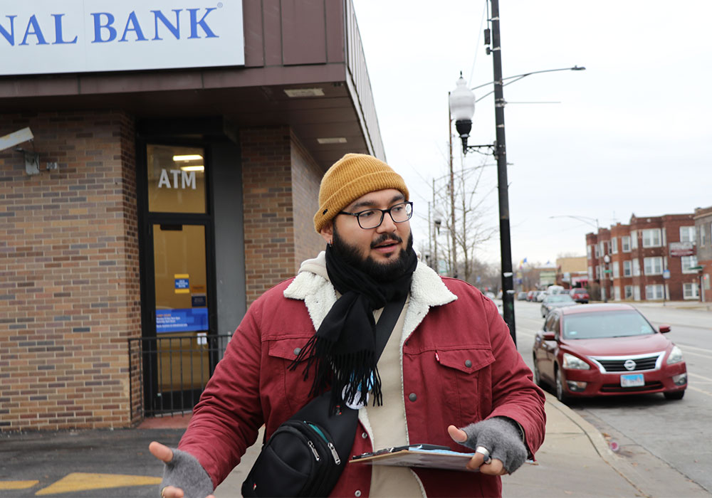 Oscar Sanchez walks down a sidewalk holding a clipboard.