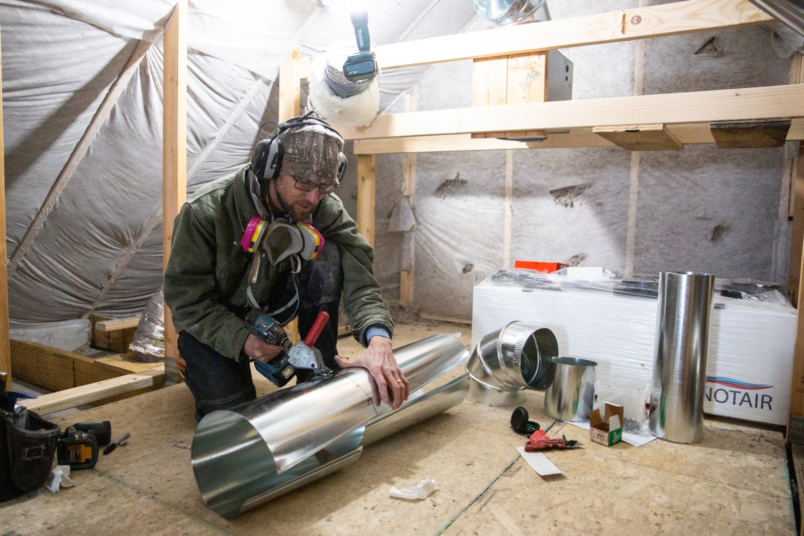 A man wearing large headphones rolls a metal sheet.