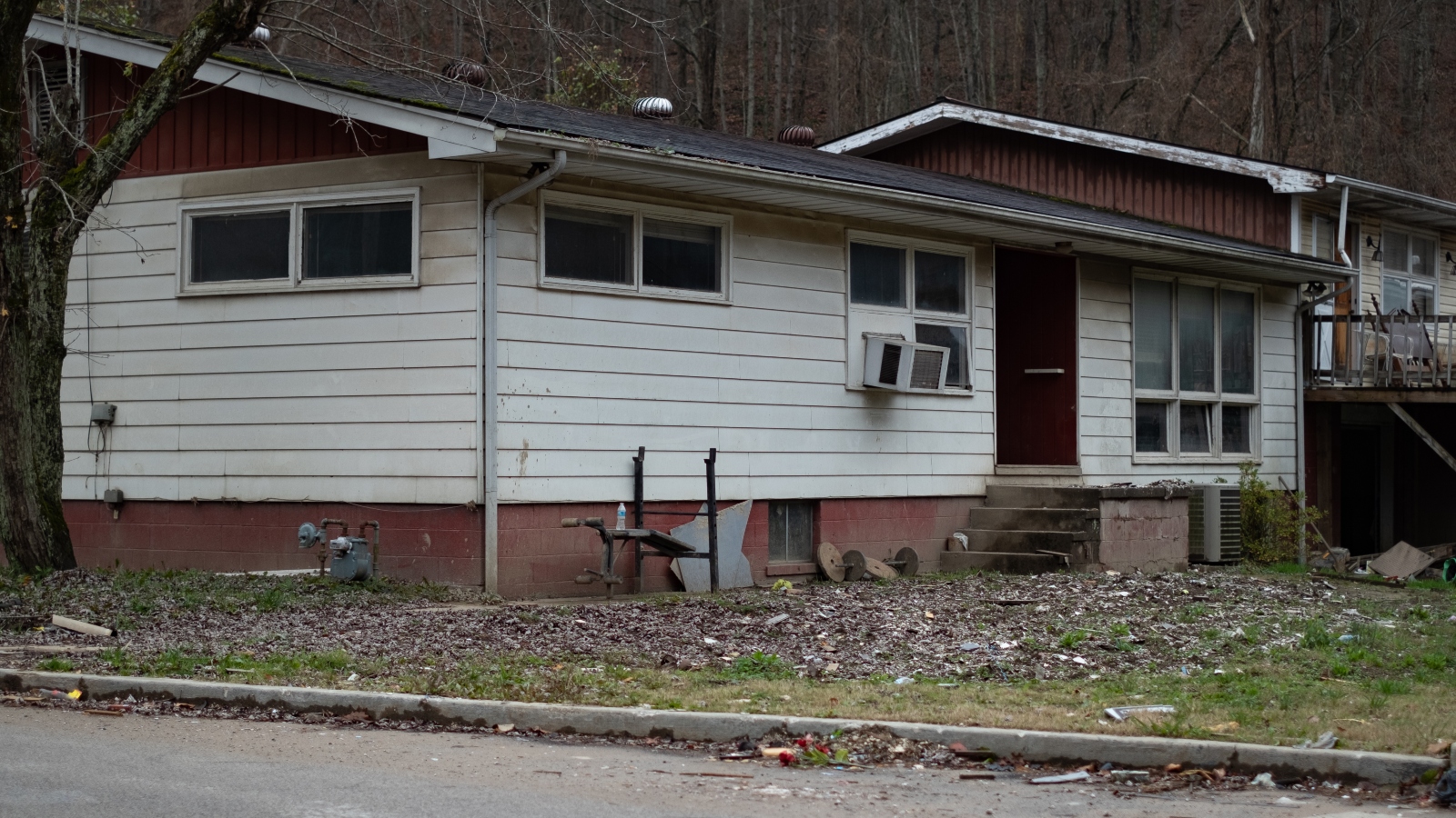 a split level house showing flood damage with leaves on the grass.