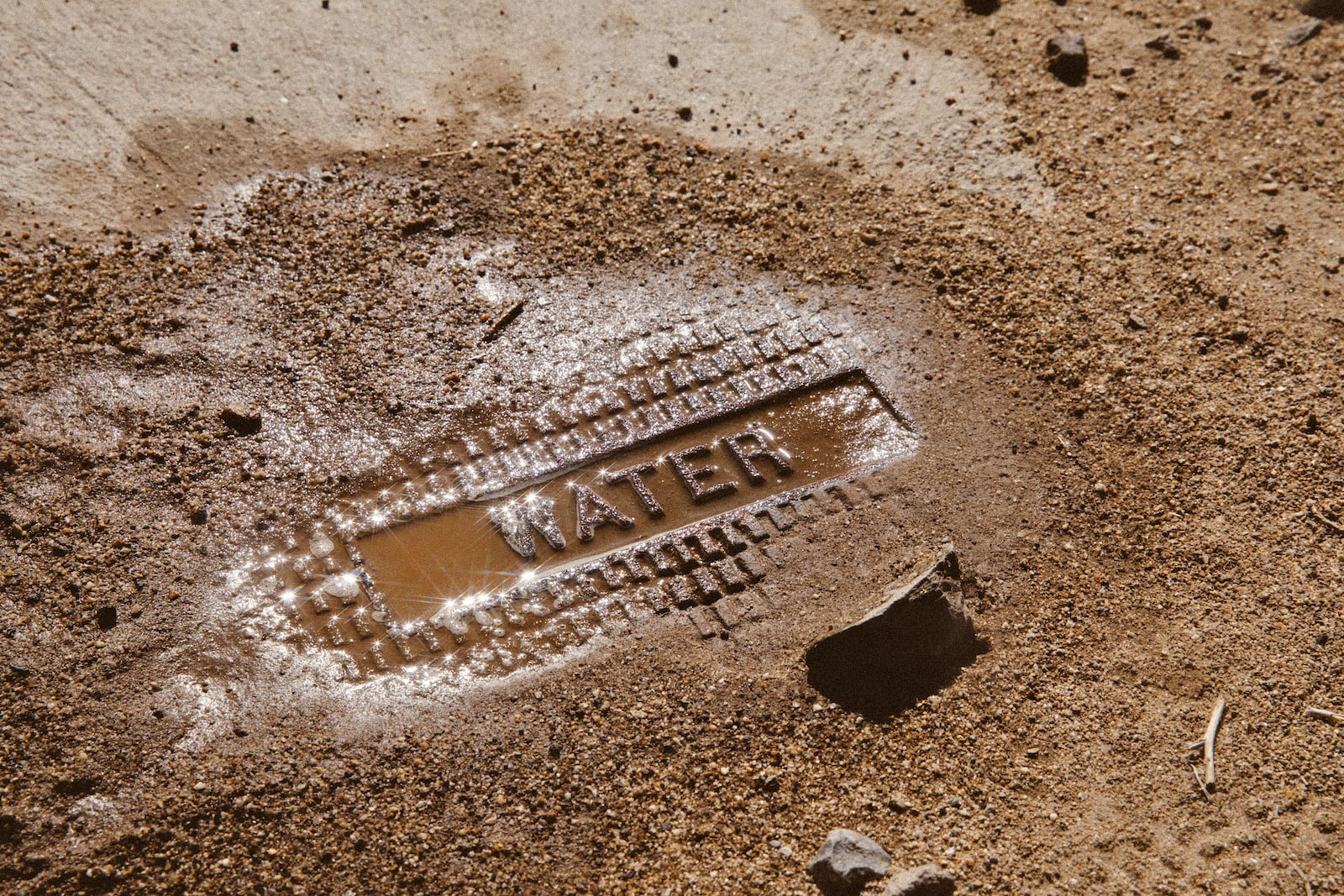 a dirty metal ground grate reads "water"