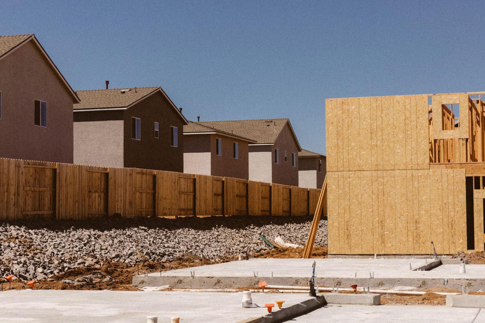 a half-built wall next to a line of houses and a fence