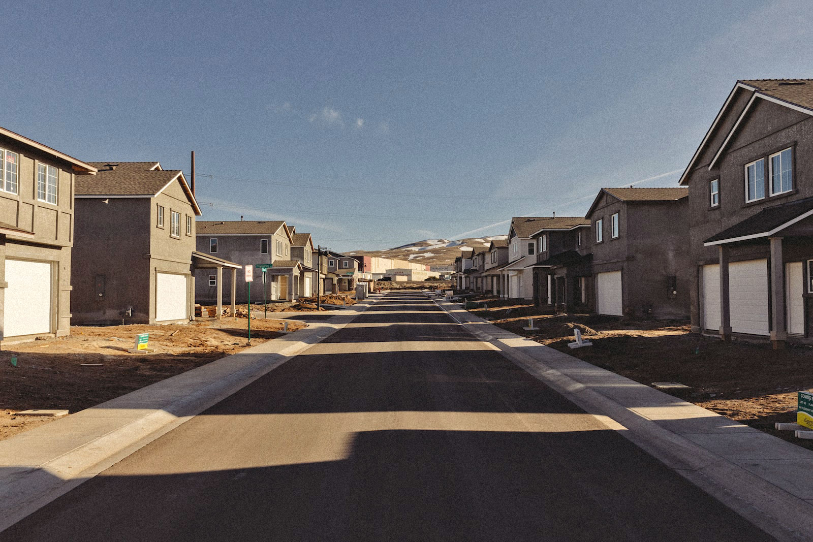 houses stand on either side of a road in a suburban housing complex