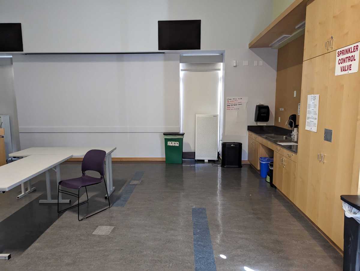 A room with a tile floor; straight ahead, a rectangular white air filtration device sits in front of a window.