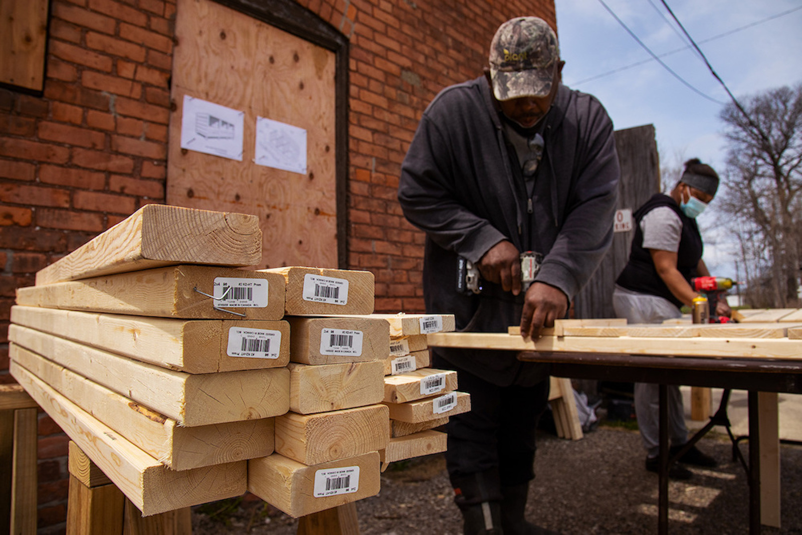 A person cuts long pieces of wood with power tools