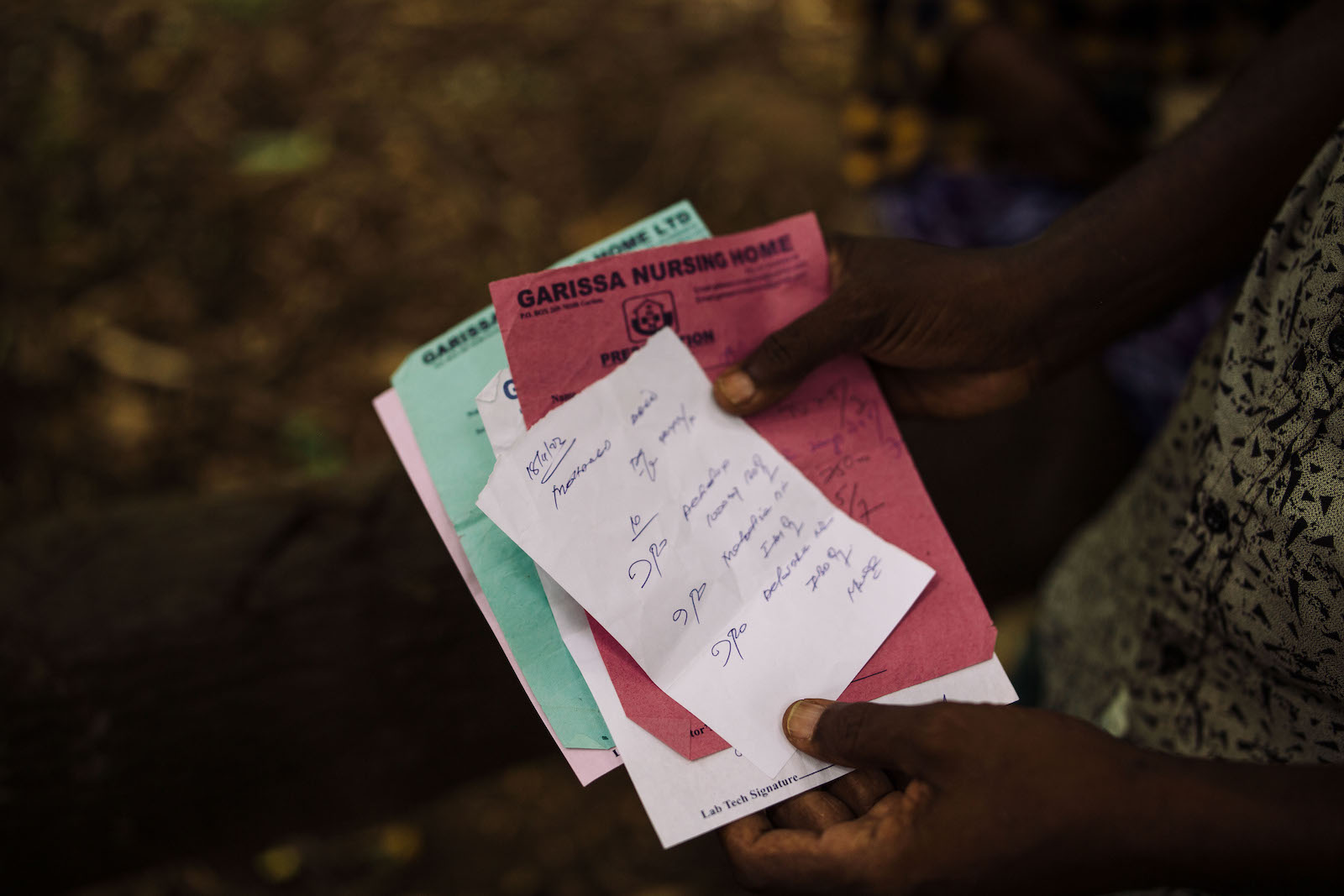 Hands hold a stack of documents of various colors