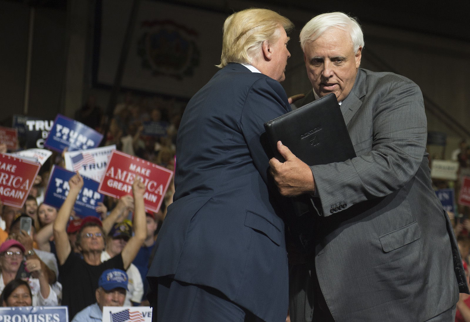 two white men in suits hug kind of