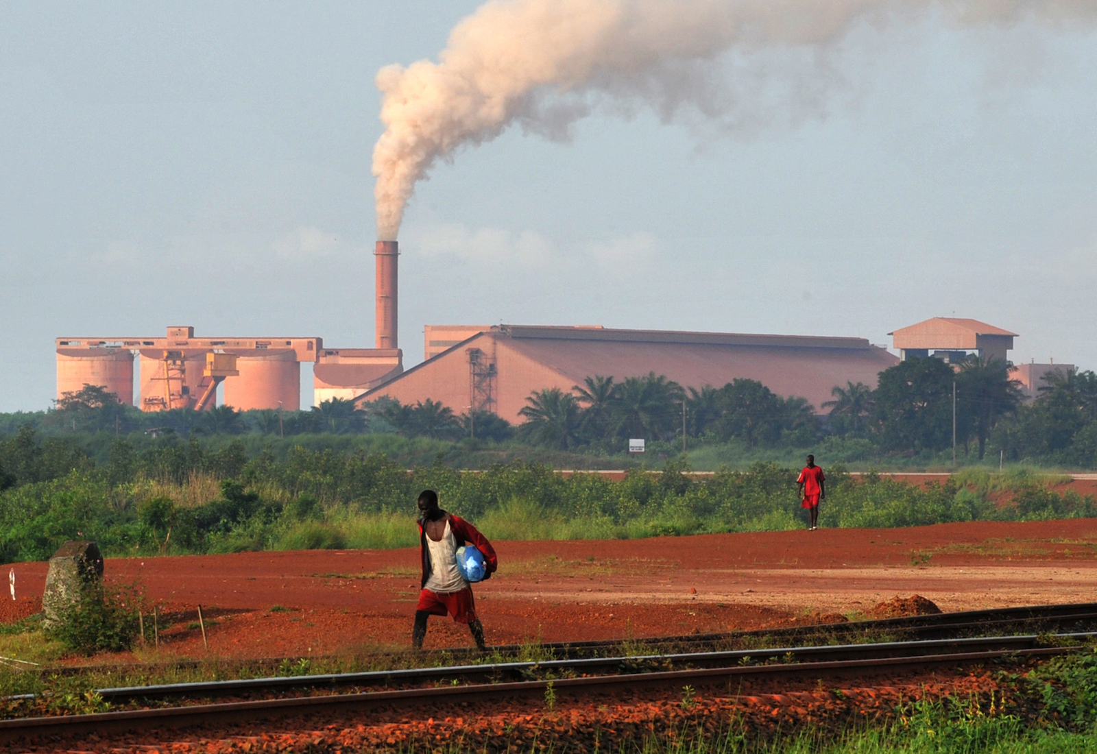 Man walking in foreground with factory in background