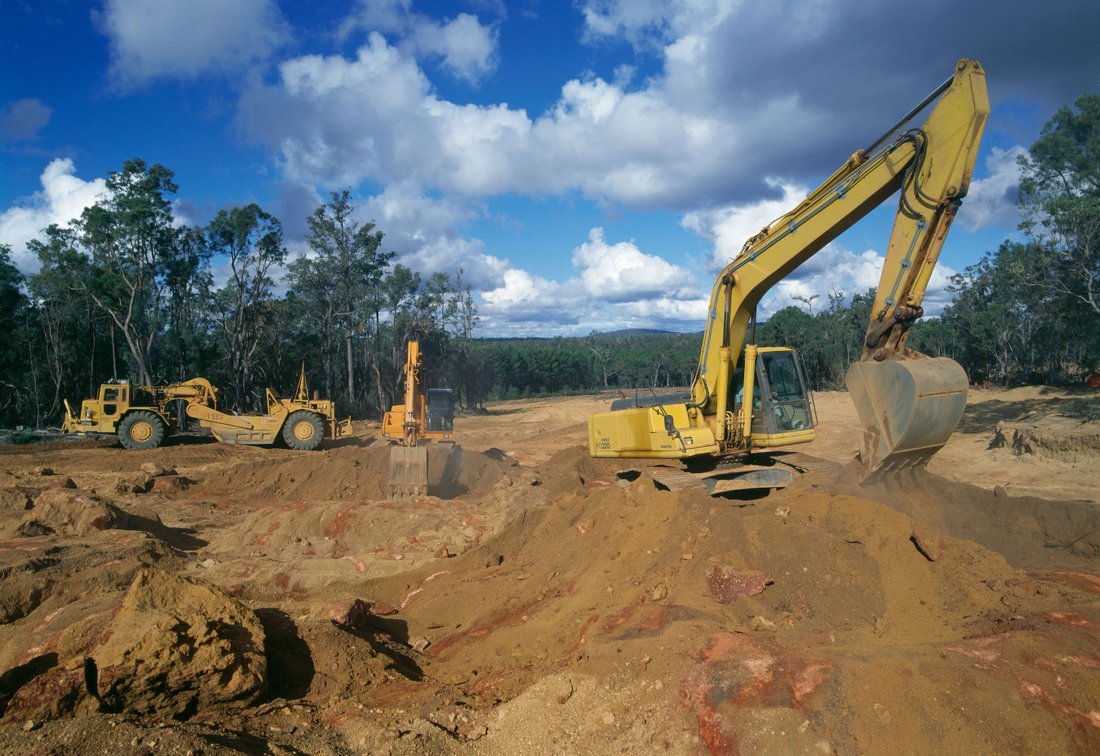 A strip mine with yellow machinery