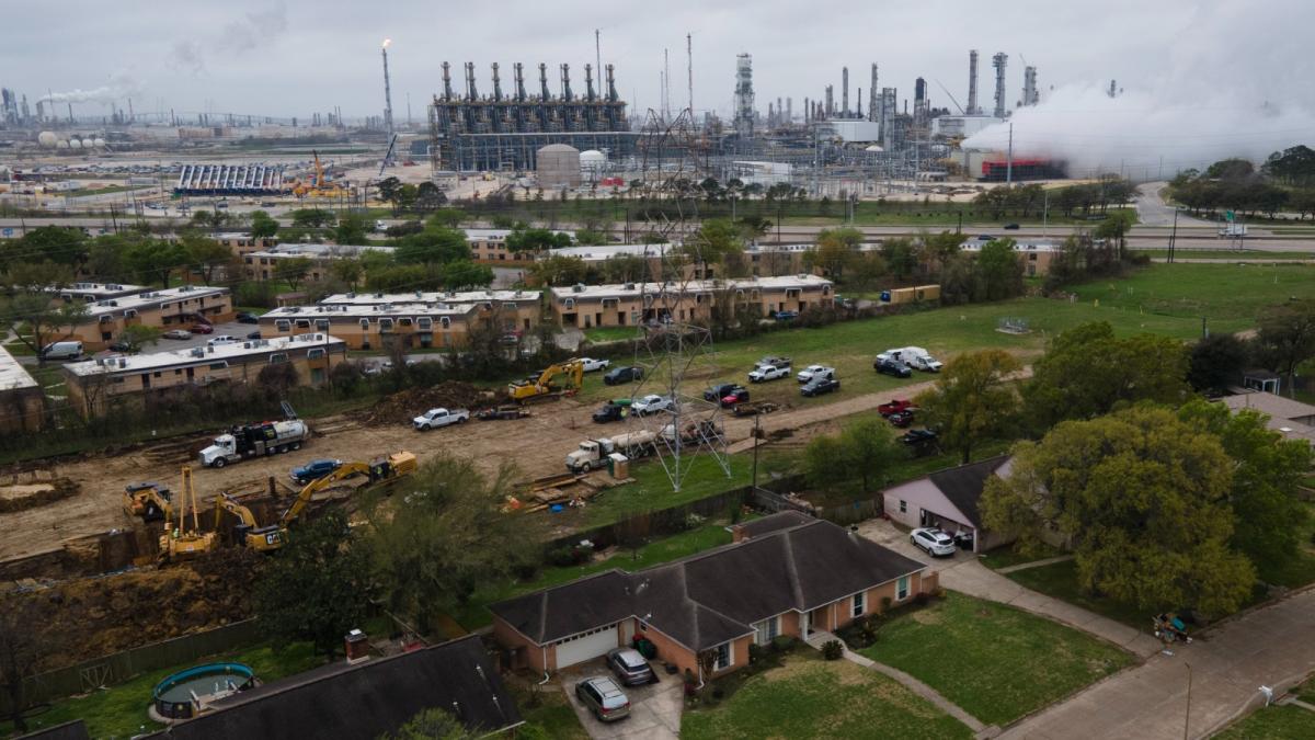 An overhead shot of a house next door to a large industrial refinery.