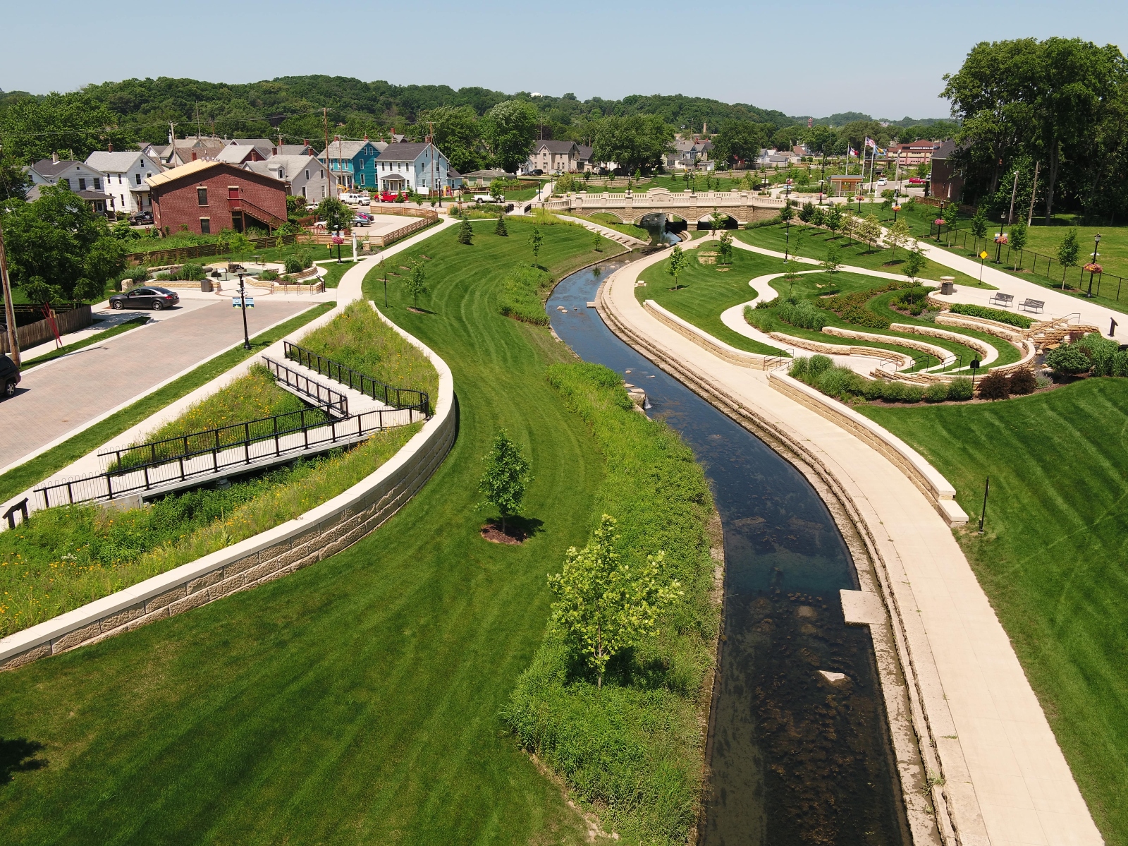 A creek runs through landscaped grass in a tidy town.