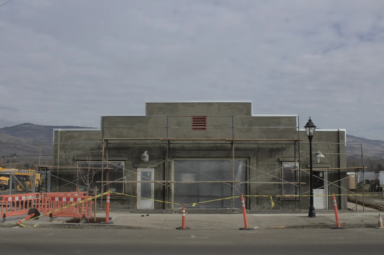 The facade of a burned building with traffic cones out front.